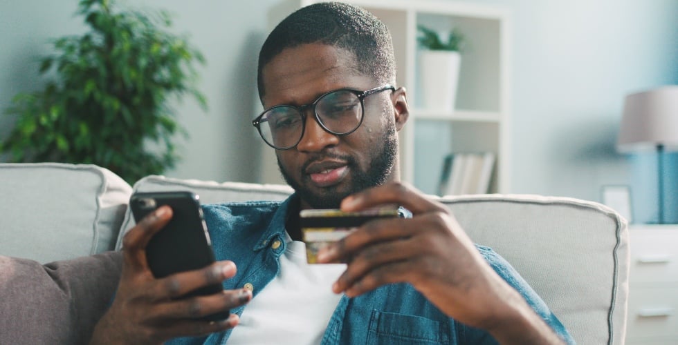 man shopping on his phone holding his credit card